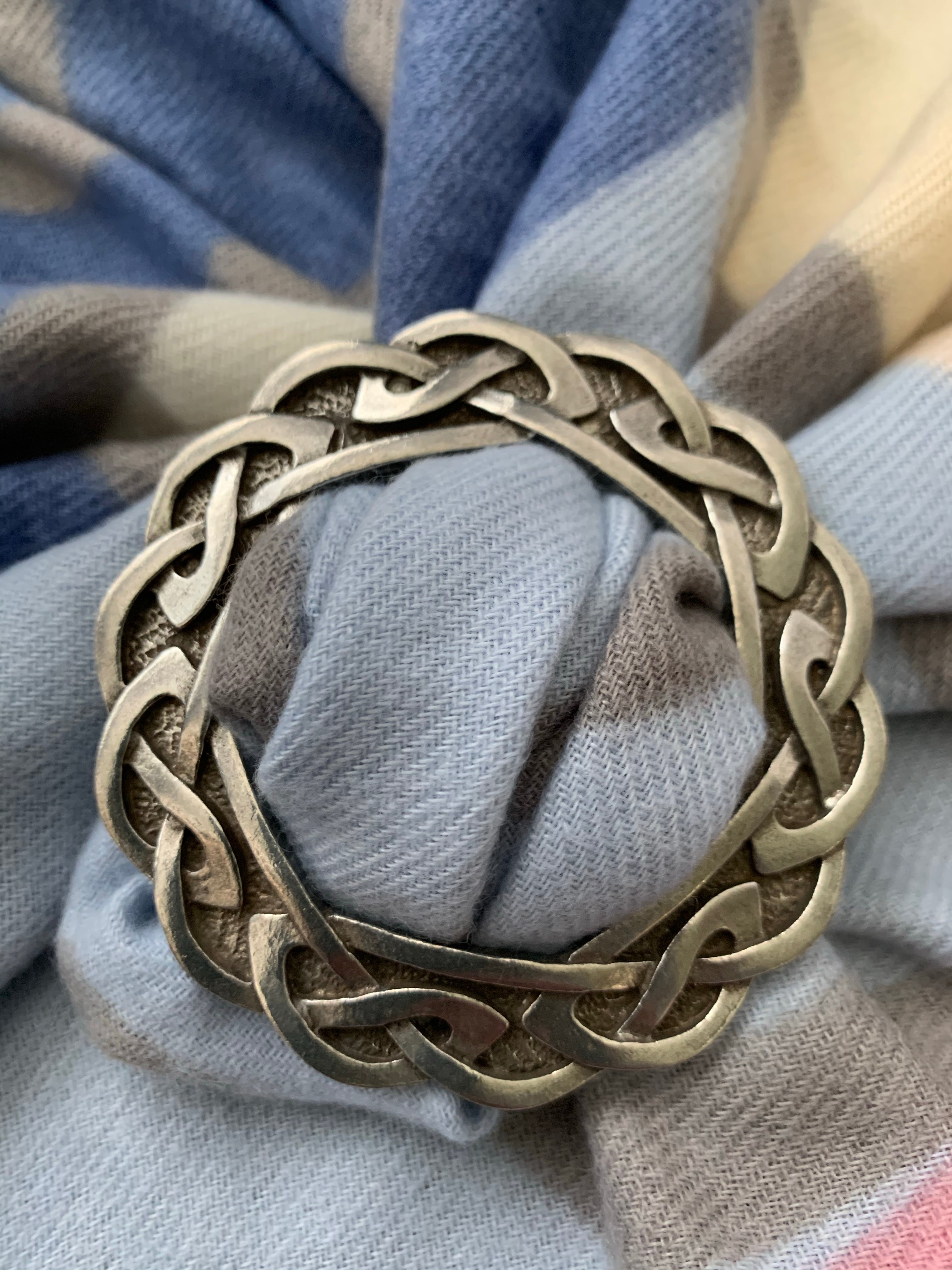 Silver antique old Celtic scarf ring with traditional design border in  sand.. Hand made traditional jewellery concept Stock Photo